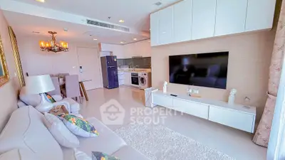 Modern open-plan living room with sleek kitchen, large TV, and stylish decor in a bright apartment.