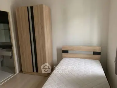 Cozy bedroom with minimalist design featuring a single bed and wooden wardrobe.