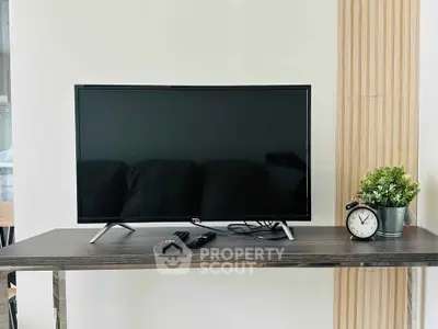 Modern living room setup with sleek TV and stylish decor on wooden table.