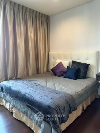 Cozy bedroom with elegant curtains and plush bedding in a modern apartment.