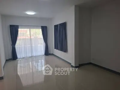 Spacious unfurnished room with large windows and blue curtains, perfect for customization.