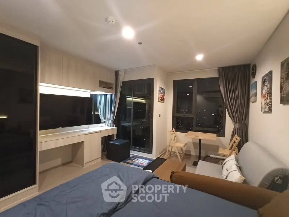 Modern studio apartment with large windows and stylish decor, offering a cozy living space with city views.