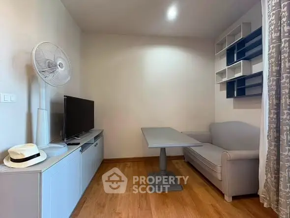Cozy living room with modern decor, featuring a TV, fan, and stylish shelving.