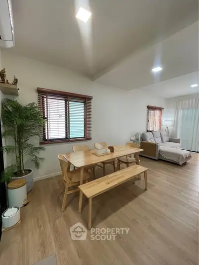 Spacious living room with wooden dining set and cozy seating area, perfect for family gatherings.