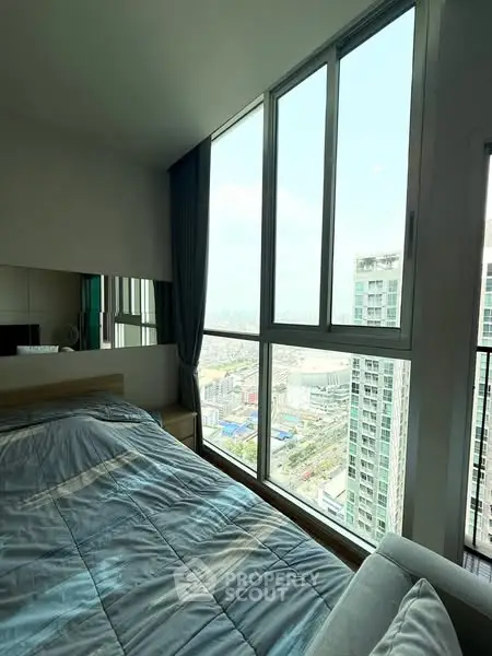 Modern bedroom with large windows offering stunning city view in high-rise apartment.