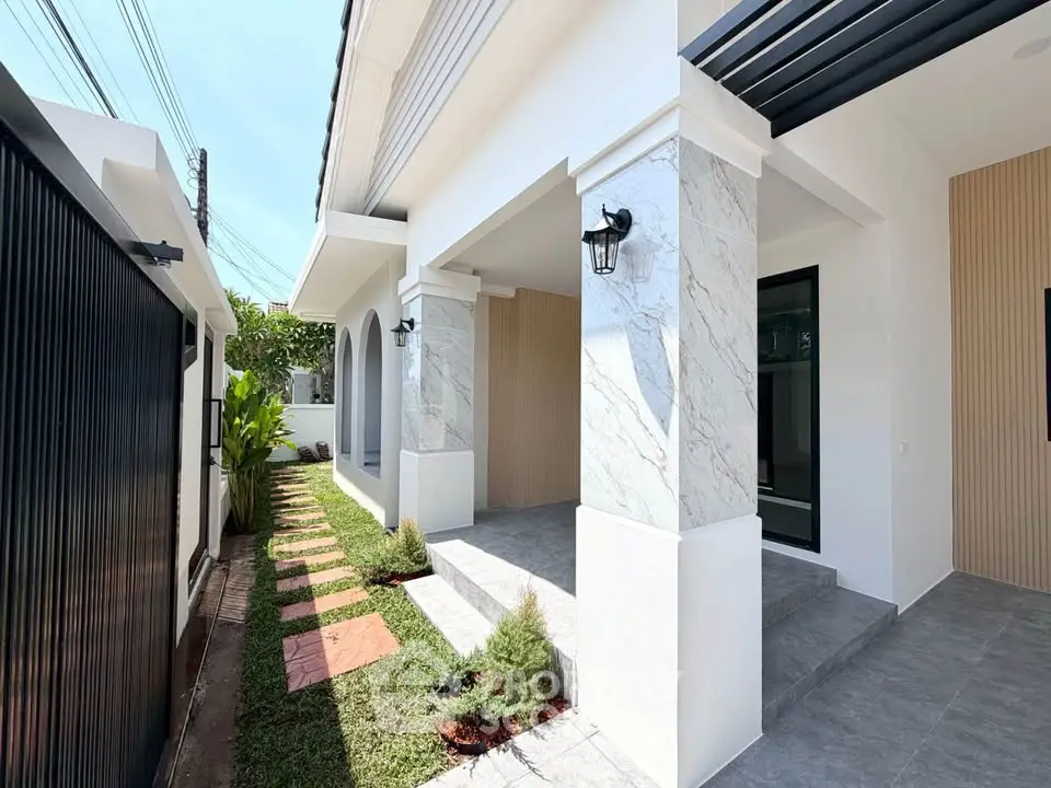Elegant modern house exterior with stylish columns and lush garden pathway.