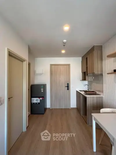 Modern apartment interior with compact kitchen and wooden flooring, showcasing efficient use of space.