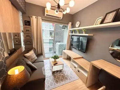 Modern living room with stylish decor and balcony view, featuring a cozy sofa and wall-mounted TV.