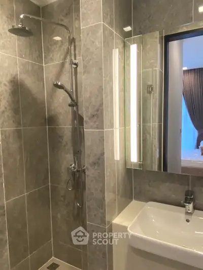 Modern bathroom with sleek shower and illuminated mirror in luxury apartment.