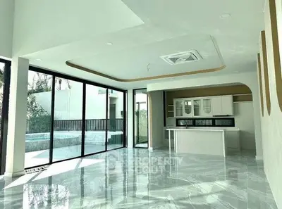 Luxurious open-plan living area with modern kitchen and large windows overlooking a private pool.