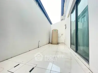 Spacious outdoor area with sleek tiled flooring and modern design, perfect for relaxation or storage.