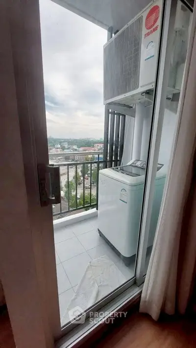 Compact balcony with washing machine and city view, ideal for urban living.