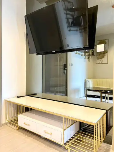 Modern living room with sleek TV stand and mounted flat-screen TV, featuring elegant gold accents and contemporary design.