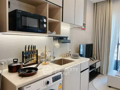 Modern kitchen with sleek appliances and open shelving in a stylish apartment.