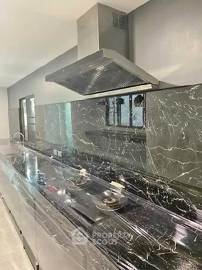 Modern kitchen with sleek black marble countertops and stainless steel appliances.
