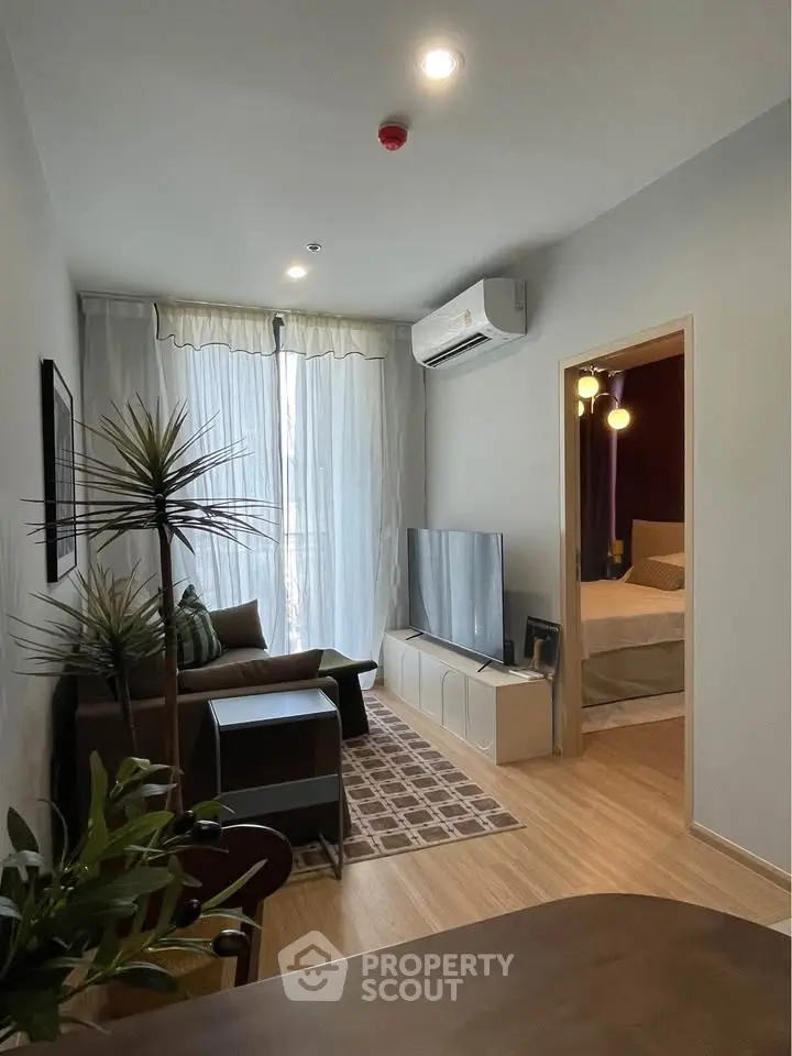 Modern living room with sleek furniture and natural light, adjacent to a cozy bedroom.