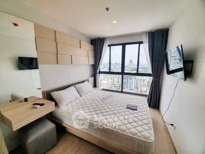 Modern bedroom with city view, featuring a large window, wall-mounted TV, and stylish decor.