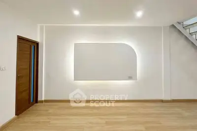 Modern minimalist interior with wooden flooring and unique wall lighting feature.
