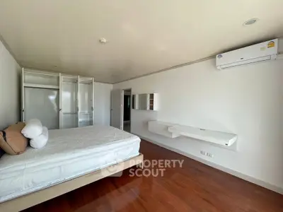 Spacious bedroom with modern design and wooden flooring, featuring built-in wardrobe and air conditioning.
