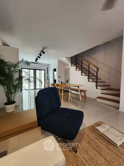 Modern living room with stylish furniture and staircase, featuring open layout and natural light.