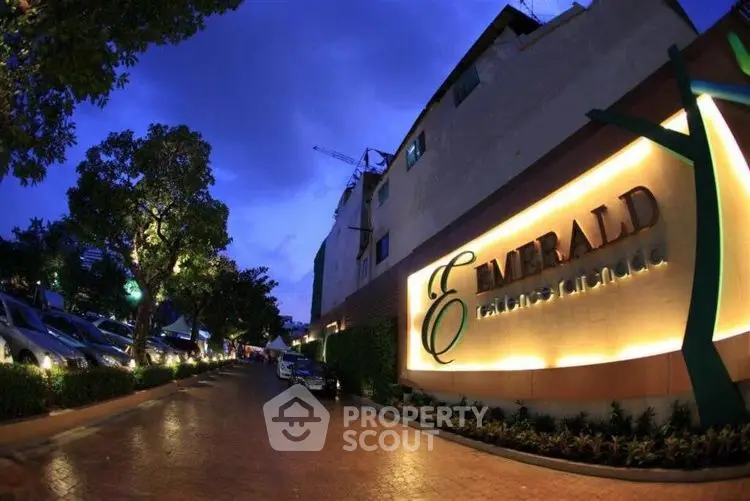 Elegant exterior view of Emerald building with illuminated signage and lush surroundings.