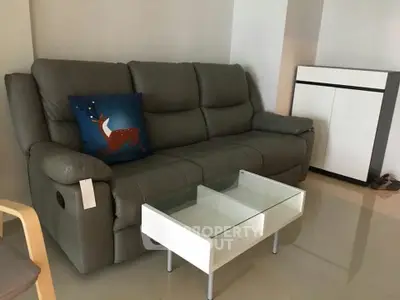 Modern living room with sleek gray sofa and stylish glass coffee table.