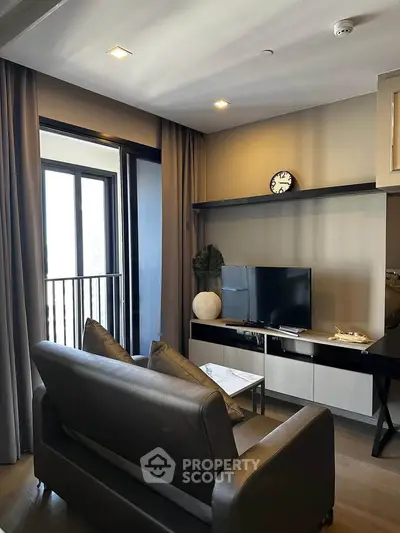 Modern living room with sleek furniture and large window offering natural light.
