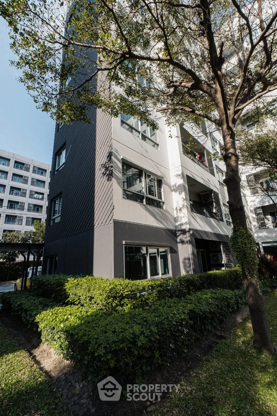 Modern apartment building exterior with lush greenery and contemporary design.
