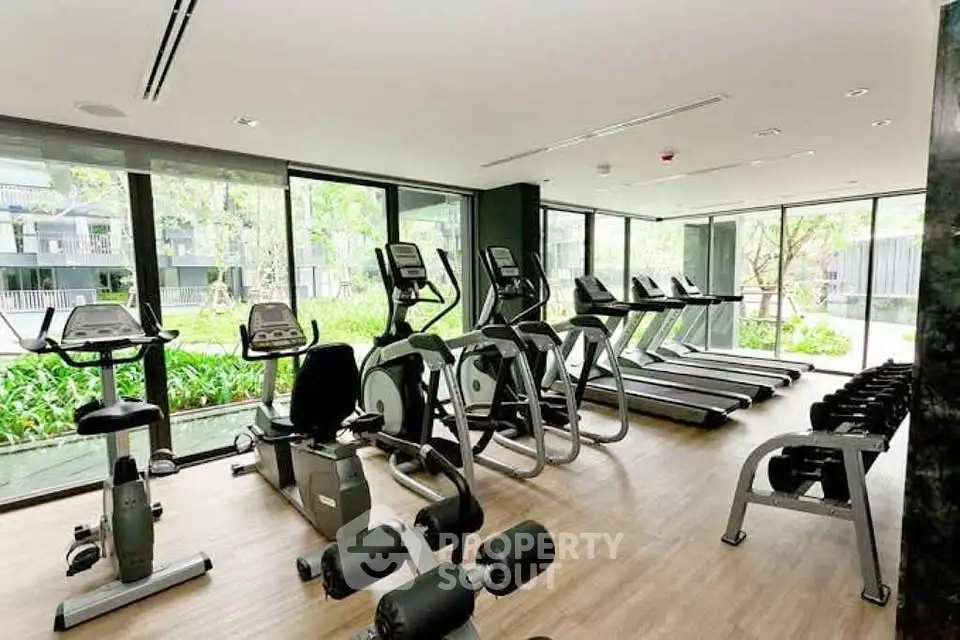 Modern gym with state-of-the-art equipment and garden view in luxury condo.