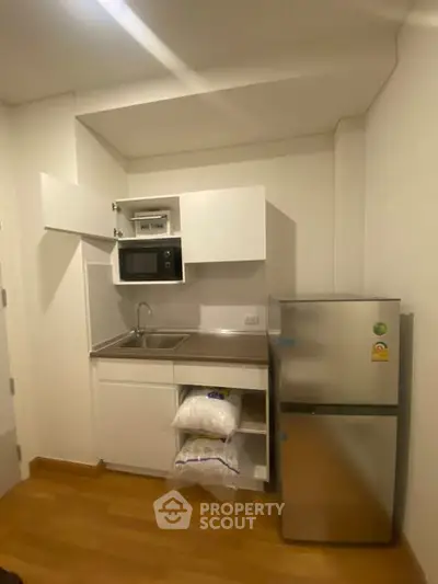 Compact kitchen with microwave, fridge, and storage in modern apartment
