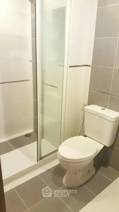 Modern bathroom with sleek shower and toilet in neutral tones.