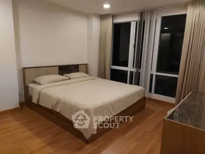 Spacious bedroom with large windows and elegant wooden flooring