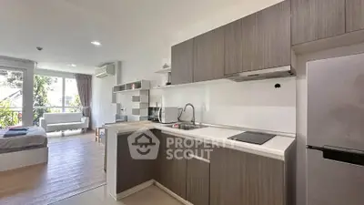 Modern open-layout kitchen with sleek cabinetry and bright living area in a stylish apartment.