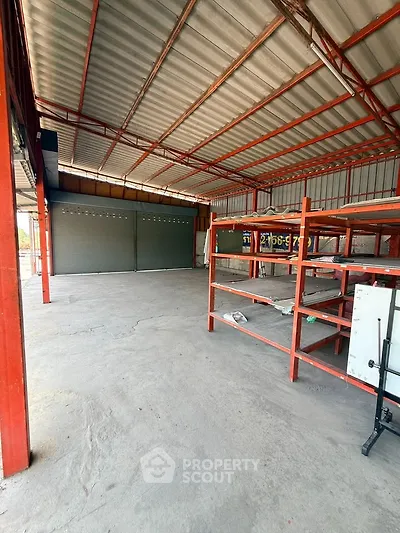 Spacious industrial warehouse with metal shelving and large garage doors, ideal for storage or business operations.