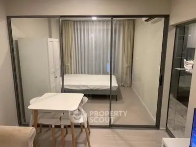 Modern studio apartment with glass partition, cozy dining area, and elegant bedroom setup.