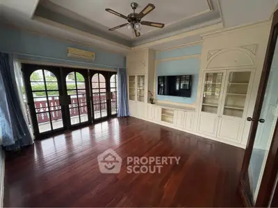 Spacious living room with elegant wooden flooring and built-in cabinets, featuring large windows for natural light.