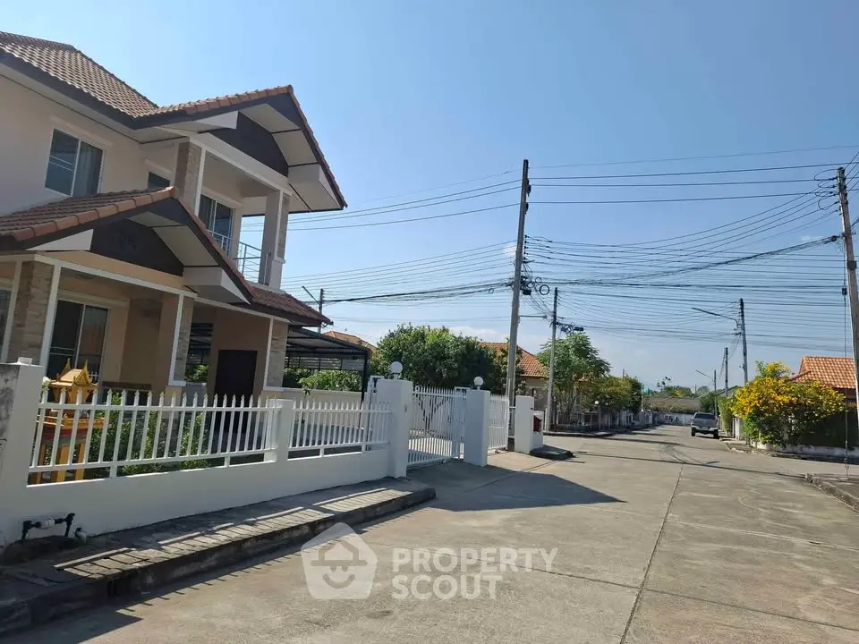 Charming suburban house with tiled roof and white picket fence on a sunny day.