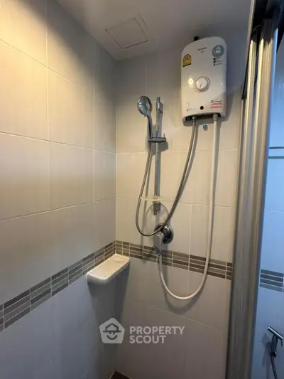 Modern bathroom with sleek shower and water heater in elegant tiled setting.