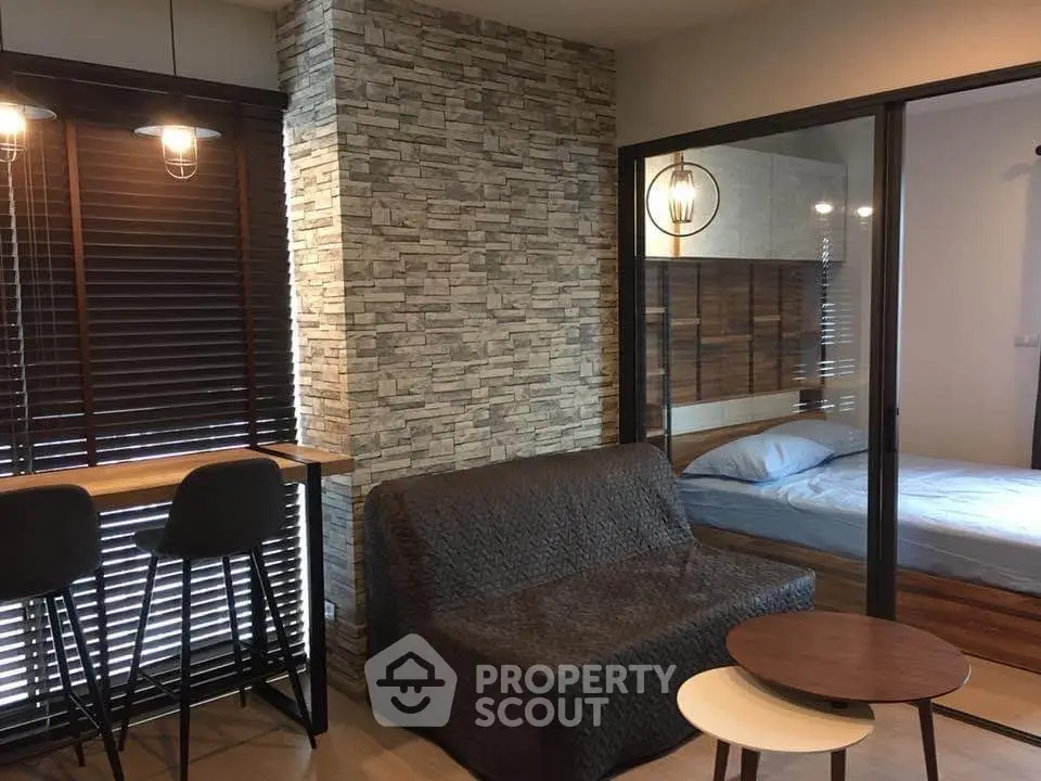 Modern apartment with stylish living room and cozy bedroom separated by glass wall.