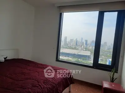 Modern bedroom with stunning city view from large window, featuring cozy red bedding and minimalist decor.