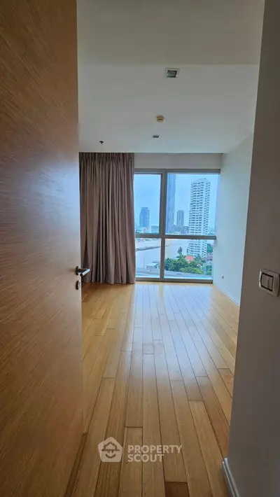 Spacious bedroom with city view and wooden flooring in modern apartment