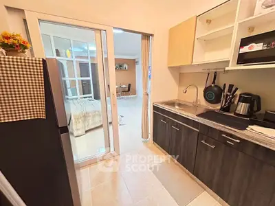 Modern kitchen with sleek cabinetry and open layout leading to a bright living area.