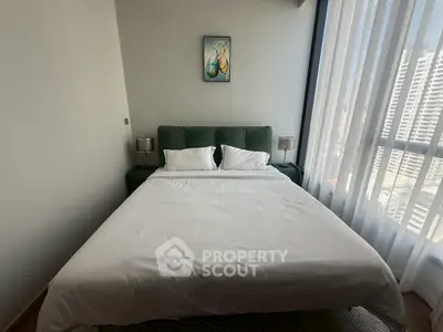 Modern bedroom with large window and stylish decor in urban apartment.