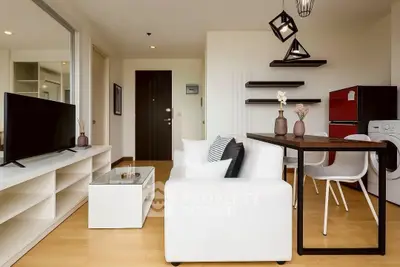 Modern living room with stylish furniture and open layout, featuring a TV and dining area.