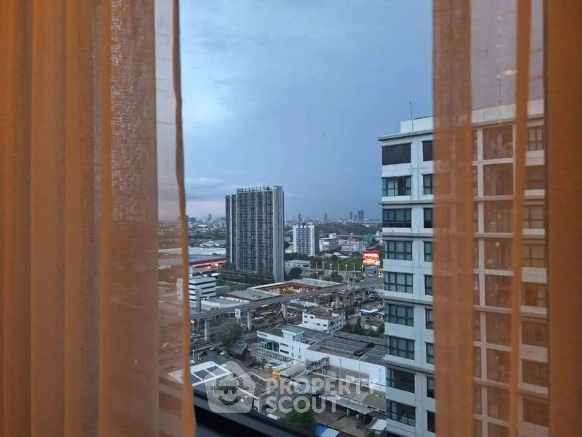 Stunning cityscape view from high-rise apartment window with sheer curtains.