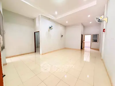 Spacious empty room with tiled flooring and ceiling fans, ideal for customization in a modern home.