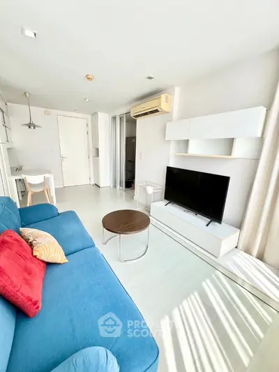 Bright and airy modern living room with a vibrant blue sofa, sleek white entertainment unit, and ample natural light streaming in, perfect for relaxed living and entertaining.