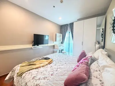 Cozy bedroom with modern decor, featuring a wall-mounted TV and a study nook by the window.