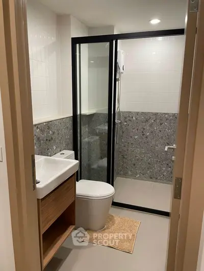 Modern bathroom with sleek shower and stylish vanity in contemporary apartment.