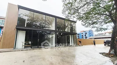 Modern commercial building with large glass facade and spacious parking area.